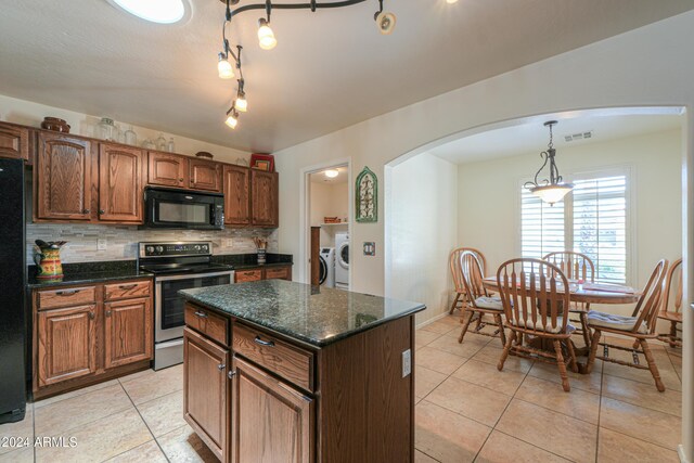 kitchen featuring separate washer and dryer, tasteful backsplash, black appliances, a center island, and light tile patterned flooring