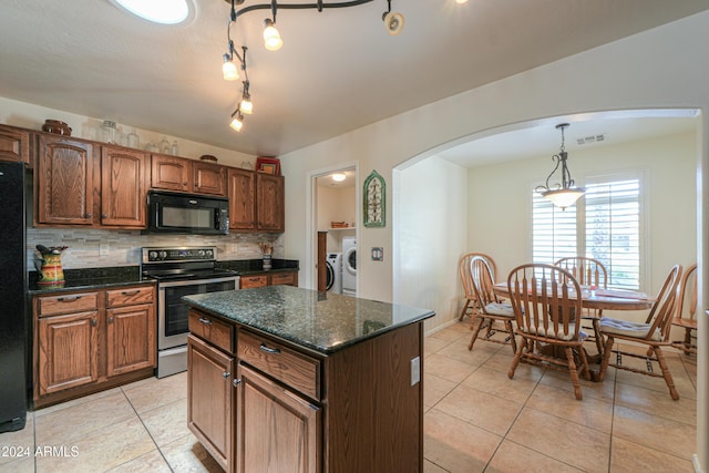 kitchen with arched walkways, decorative light fixtures, washing machine and clothes dryer, a kitchen island, and black appliances