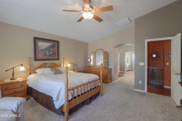 bedroom featuring arched walkways, visible vents, ensuite bathroom, light carpet, and vaulted ceiling