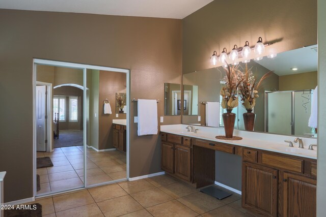 bathroom with tile patterned floors, vaulted ceiling, and dual vanity