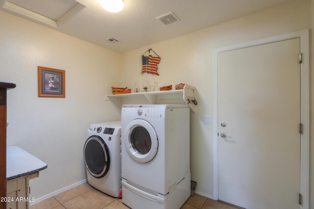 laundry area featuring laundry area, light tile patterned flooring, washing machine and dryer, and visible vents