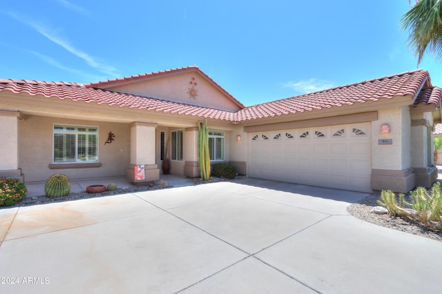 mediterranean / spanish-style house with a garage, driveway, a tiled roof, and stucco siding