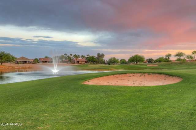 surrounding community featuring view of golf course, a yard, and a water view