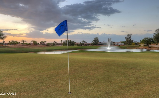 view of community featuring a water view, a lawn, and golf course view