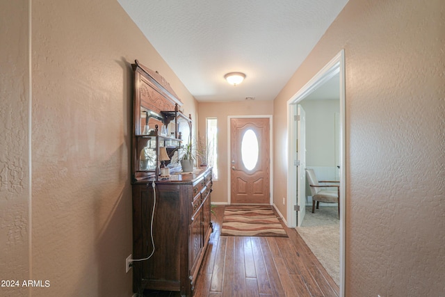 entryway featuring a textured ceiling, a textured wall, wood finished floors, visible vents, and baseboards