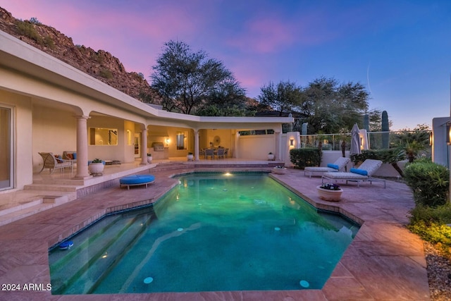 pool at dusk featuring a patio