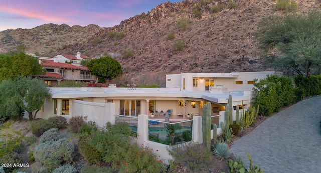 back house at dusk featuring a patio and a mountain view