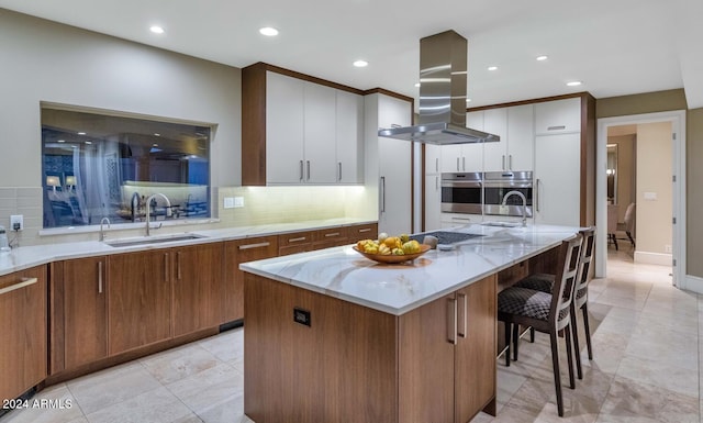 kitchen with island exhaust hood, a kitchen island, white cabinetry, decorative backsplash, and sink