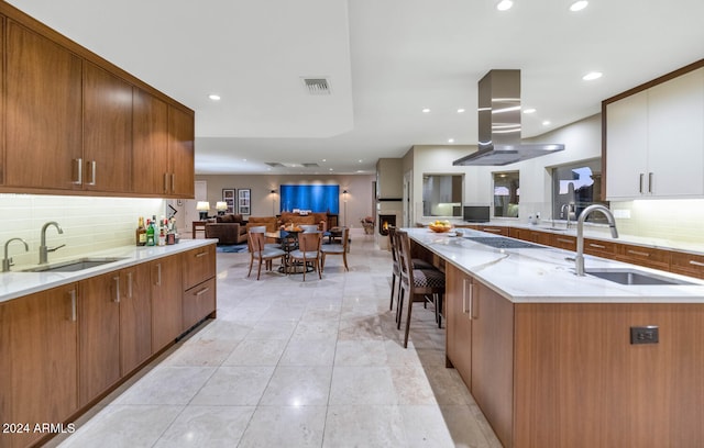 kitchen with island exhaust hood, sink, and decorative backsplash