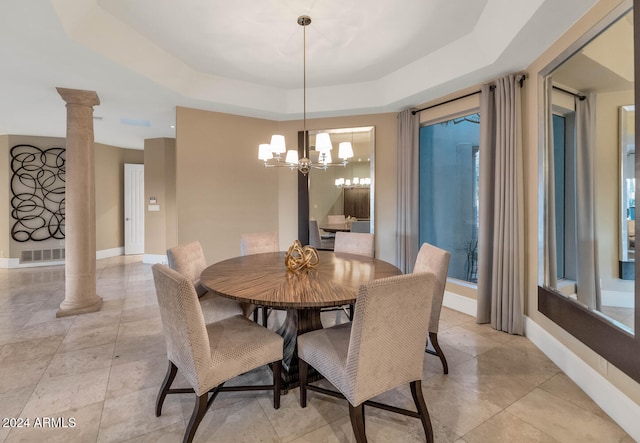 dining space with ornate columns, a notable chandelier, and a tray ceiling