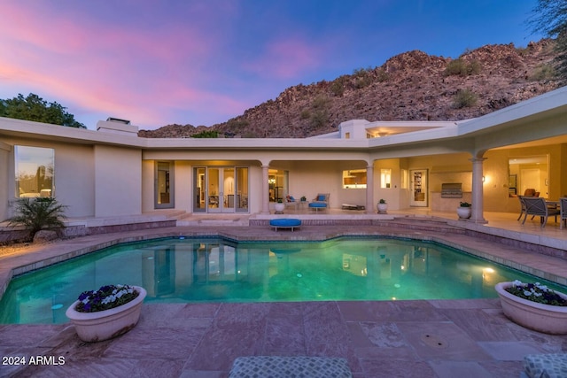 pool at dusk featuring a patio area