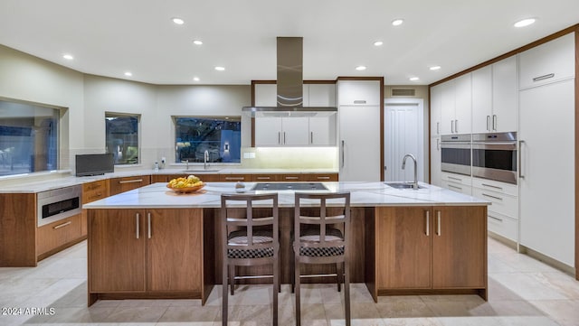 kitchen featuring white cabinets, ventilation hood, and a large island with sink