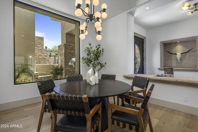 dining space with light hardwood / wood-style floors and a notable chandelier