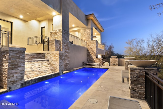 pool at dusk with an outdoor kitchen and a patio area