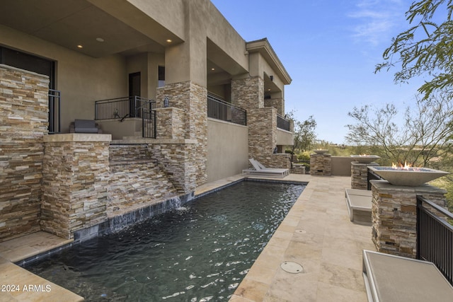 view of patio with pool water feature, an outdoor kitchen, and a balcony