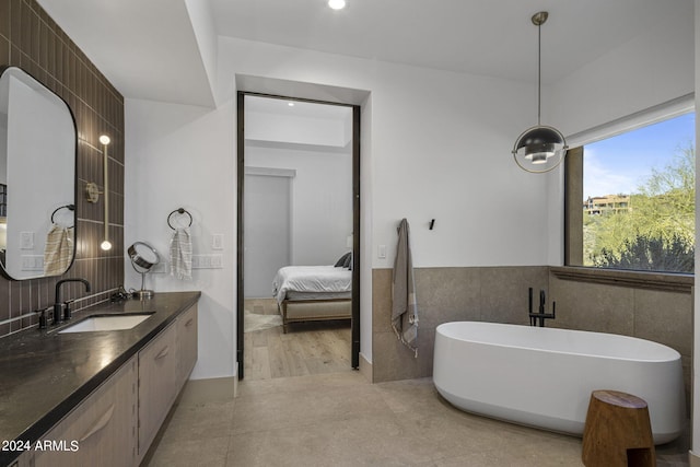 bathroom with tile patterned flooring, vanity, a bath, and tile walls