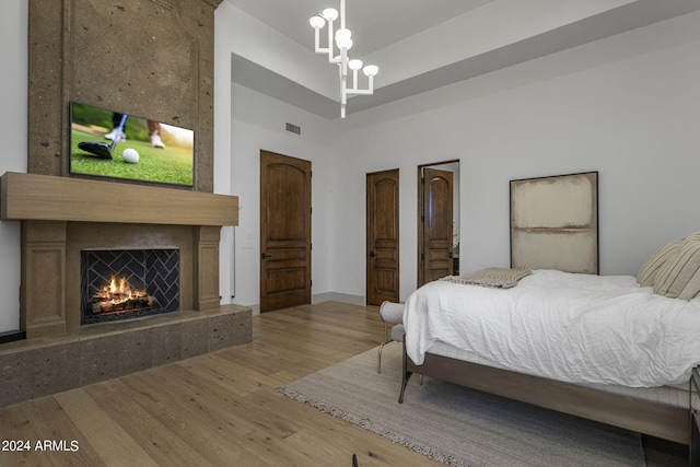 bedroom featuring hardwood / wood-style floors, a large fireplace, and a high ceiling