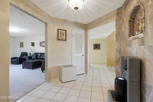 hall with a textured ceiling and light colored carpet