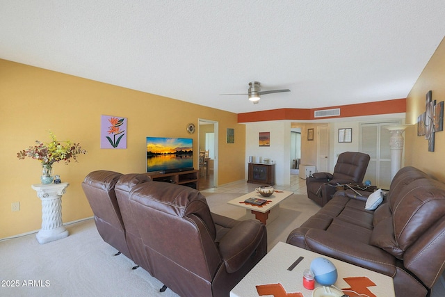 living room with a textured ceiling, ceiling fan, and light tile patterned flooring