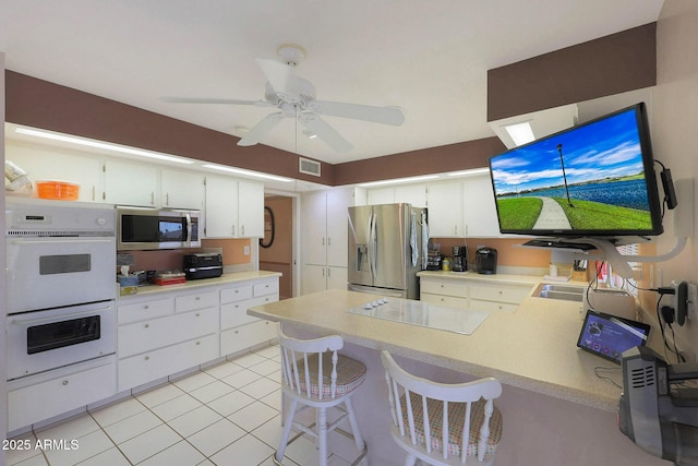 kitchen with a breakfast bar, appliances with stainless steel finishes, and white cabinetry