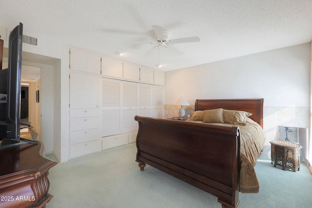 carpeted bedroom with a textured ceiling, ceiling fan, and a closet