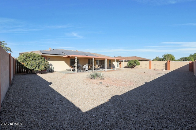 rear view of property with a patio area and solar panels