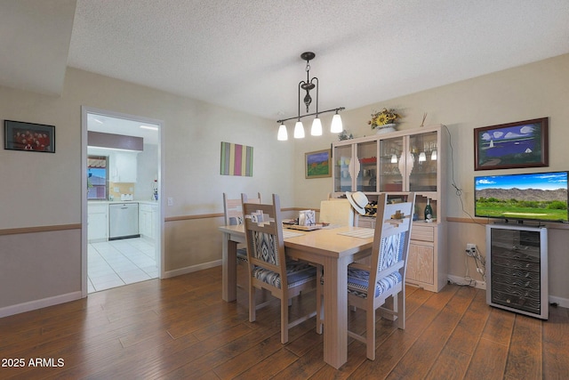 dining area featuring a textured ceiling, wine cooler, and hardwood / wood-style flooring