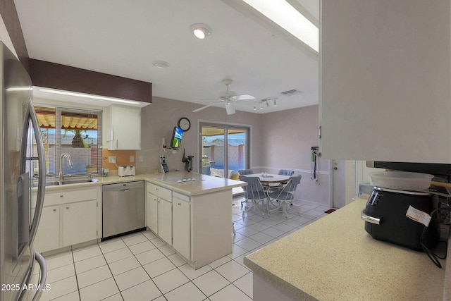 kitchen with white cabinetry, kitchen peninsula, ceiling fan, appliances with stainless steel finishes, and light tile patterned flooring