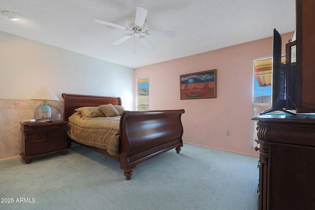 bedroom with ceiling fan, light colored carpet, and a textured ceiling