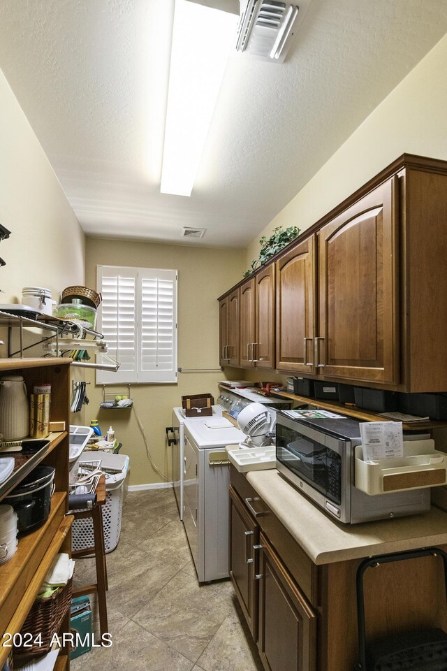 clothes washing area featuring cabinets, a textured ceiling, and washing machine and clothes dryer