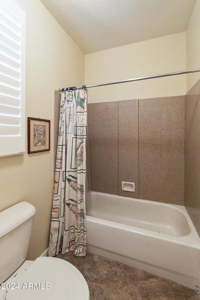 bathroom featuring shower / bath combination with curtain, tile patterned flooring, and toilet