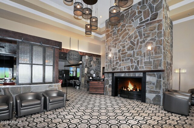 interior space with a stone fireplace, ornamental molding, and a high ceiling