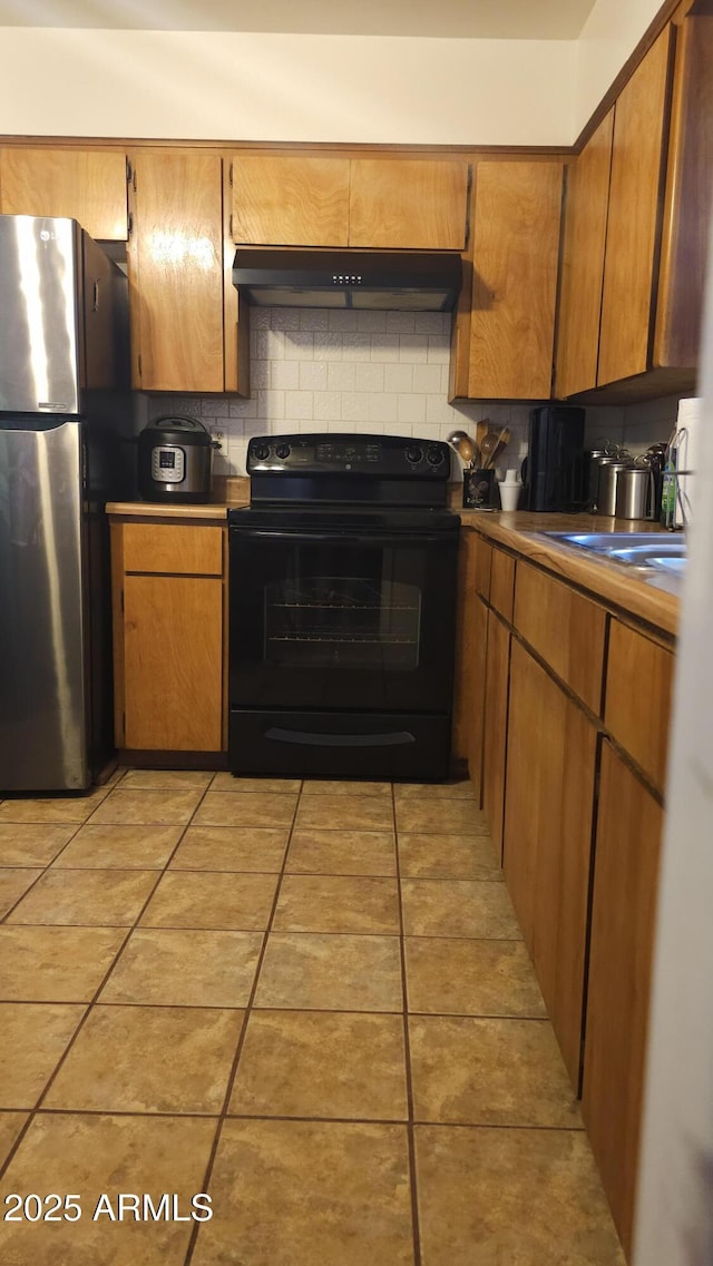 265 W 17th Ave, Apache Junction, AZ 85120 - kitchen featuring black / electric stove, freestanding refrigerator, ventilation hood, tasteful backsplash, and brown cabinetry