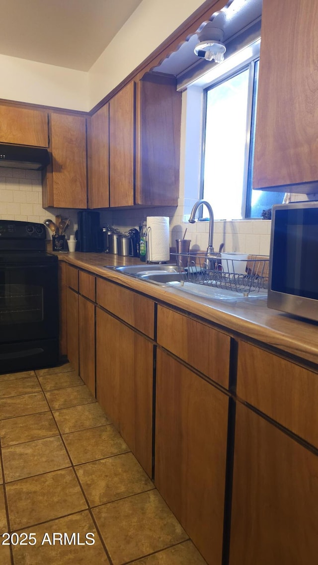 265 W 17th Ave, Apache Junction, AZ 85120 - kitchen with black electric range, stainless steel microwave, exhaust hood, decorative backsplash, and tile patterned flooring