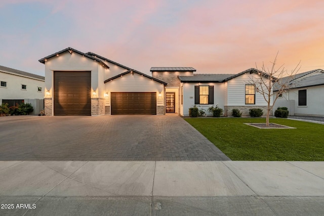 view of front of home featuring decorative driveway, roof mounted solar panels, a garage, stone siding, and a front lawn