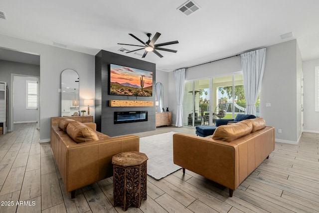 living area with light wood-type flooring, a large fireplace, and visible vents