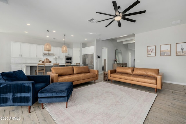 living area featuring light wood-style flooring, visible vents, baseboards, and recessed lighting