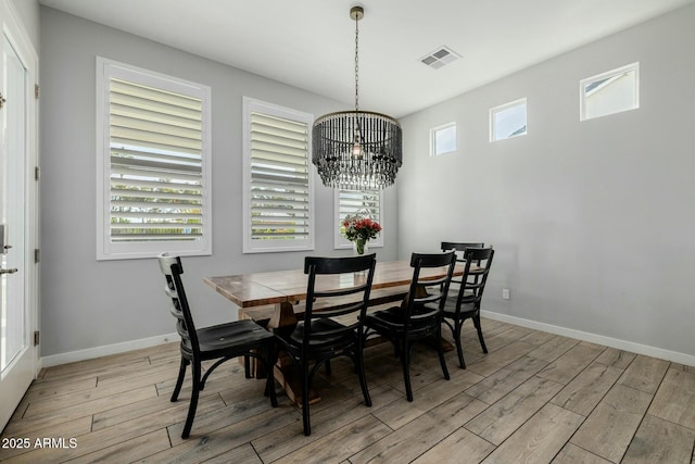 dining space featuring visible vents, a notable chandelier, light wood-style flooring, and baseboards