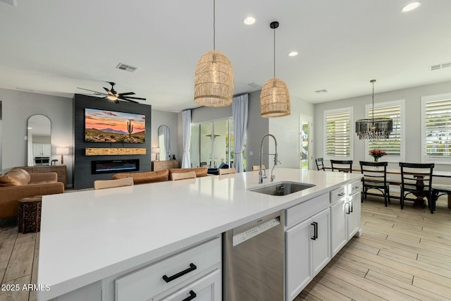 kitchen featuring a fireplace, visible vents, stainless steel dishwasher, open floor plan, and a sink