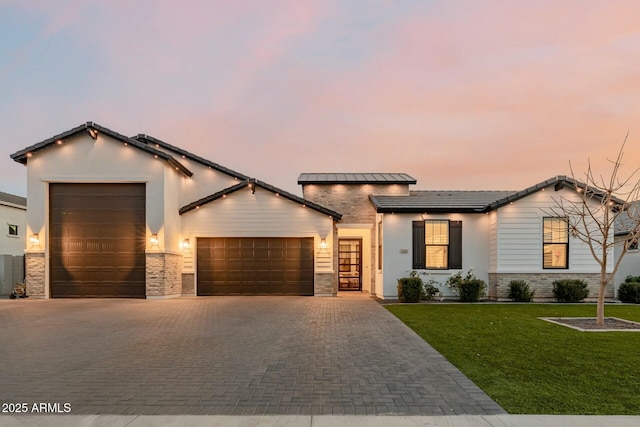 view of front of house featuring a garage, decorative driveway, and a lawn