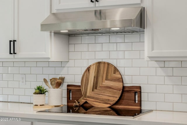 room details with tasteful backsplash, light countertops, white cabinetry, and wall chimney exhaust hood