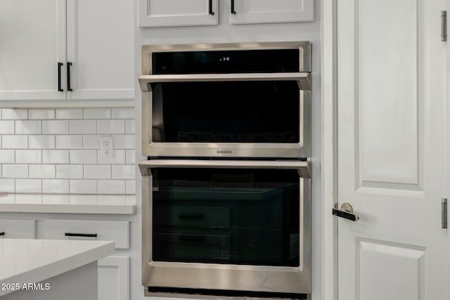 room details with double oven, light countertops, white cabinetry, and tasteful backsplash