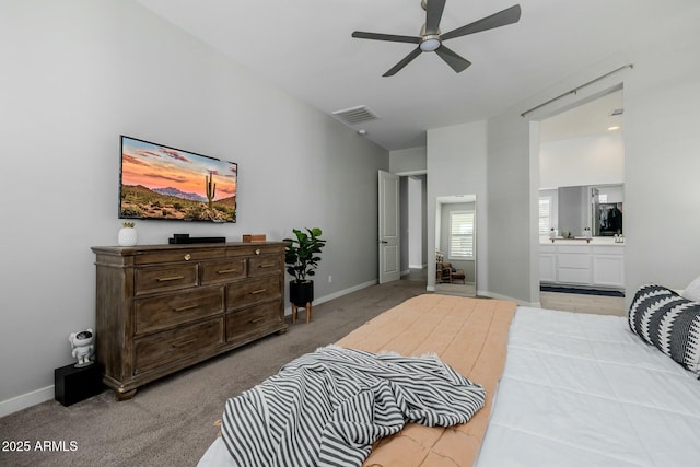 carpeted bedroom featuring ensuite bath, baseboards, visible vents, and a ceiling fan