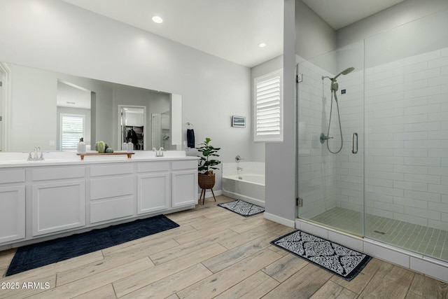 full bath featuring a sink, double vanity, a stall shower, and wood finished floors