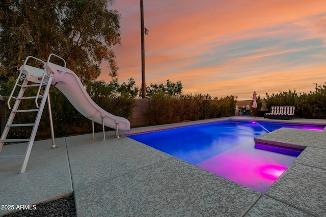 pool with fence, a water slide, and a patio