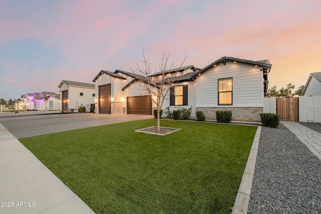 ranch-style home featuring an attached garage, solar panels, fence, concrete driveway, and a front lawn