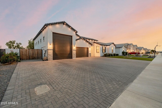 view of front of home featuring a garage, fence, decorative driveway, a gate, and stucco siding