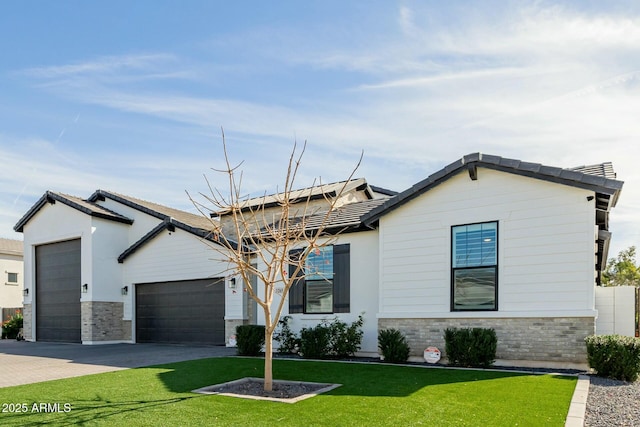 view of front of property featuring driveway, stone siding, a garage, and a front yard