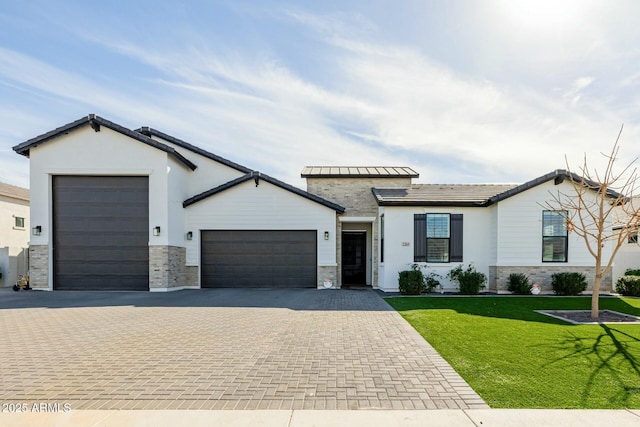 single story home featuring a garage, stone siding, a front lawn, and decorative driveway