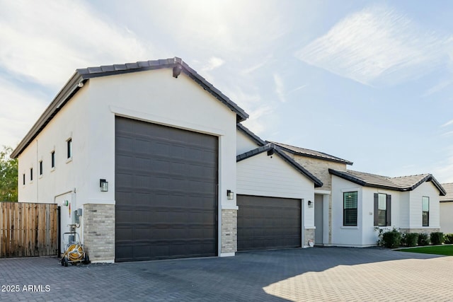 view of front of house featuring a garage, fence, decorative driveway, and stucco siding